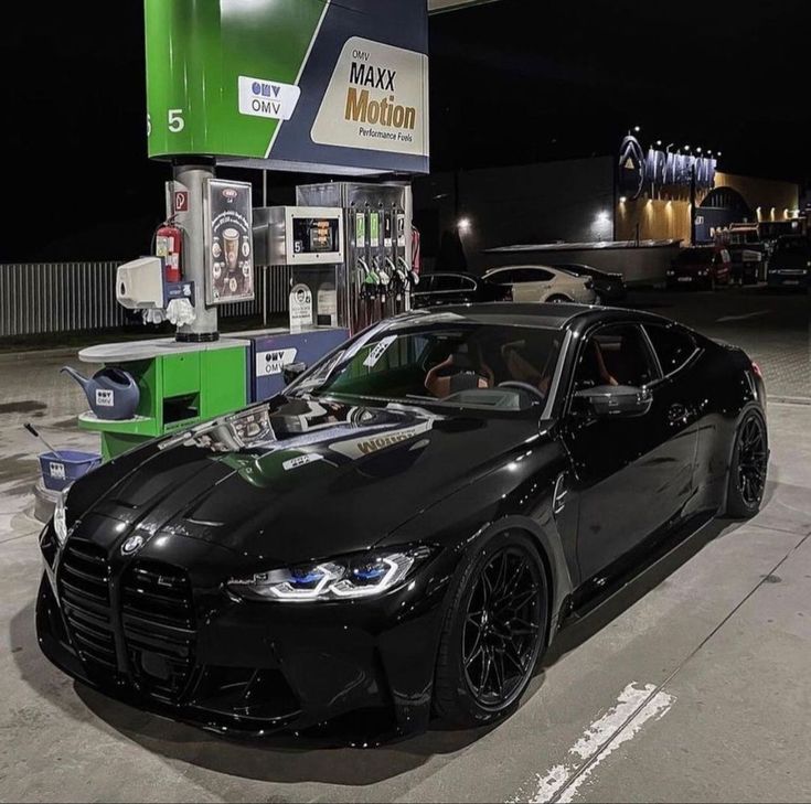 a black sports car parked in front of a gas station