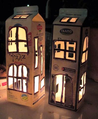 two cardboard boxes with windows and lights on them are sitting on the floor next to each other