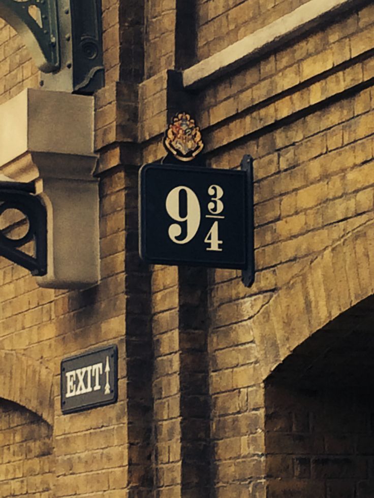 an exit sign hanging from the side of a brick building next to a traffic light