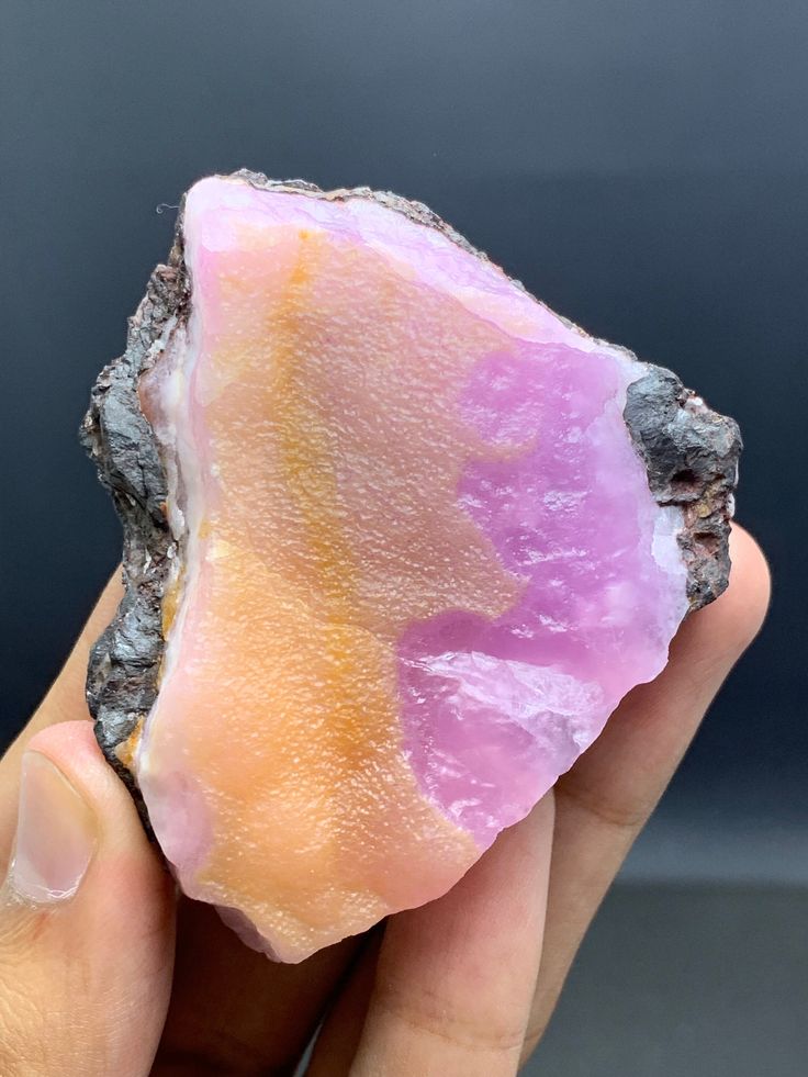 a hand holding a piece of pink and orange rock