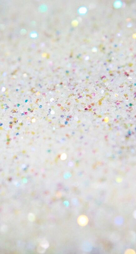 a close up view of glitter on a white surface with multicolored confetti sprinkles