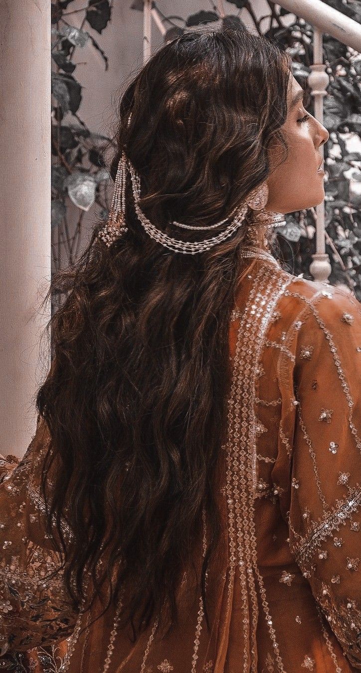 a woman with long dark hair wearing a head piece and pearls in her hair is looking off into the distance
