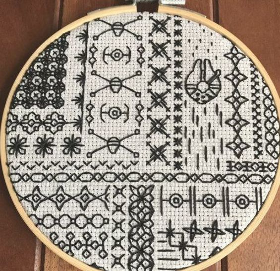 a close up of a cross stitch pattern on a wooden surface with scissors and thread