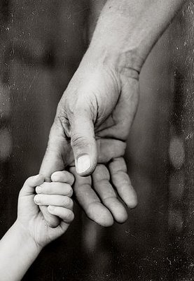 an adult holding the hand of a small child's hand in black and white