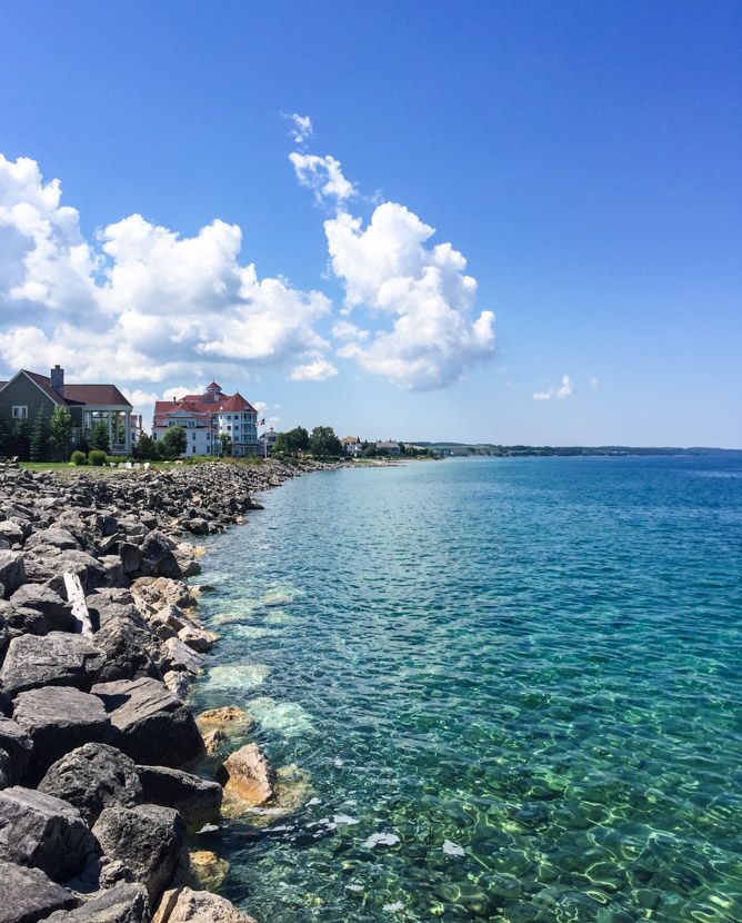 the water is crystal blue and clear as it sits next to some rocks on the shore