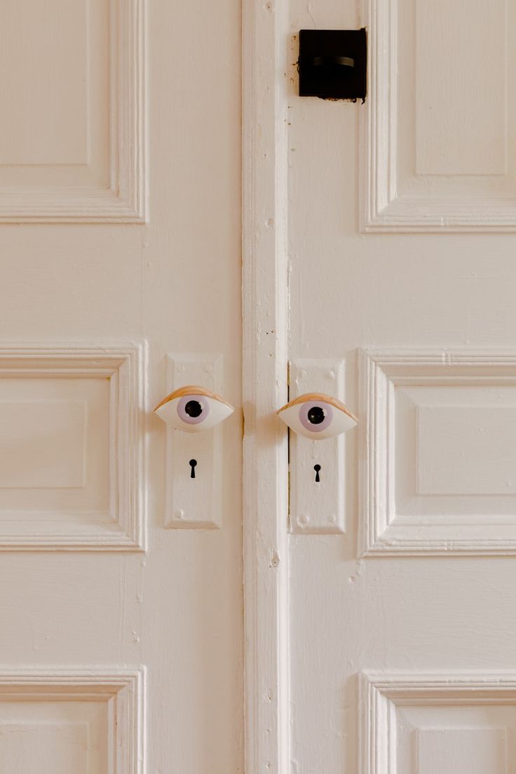 two eyeballs are on the front door of a white house with black latches