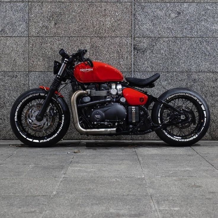 a red and black motorcycle parked next to a wall