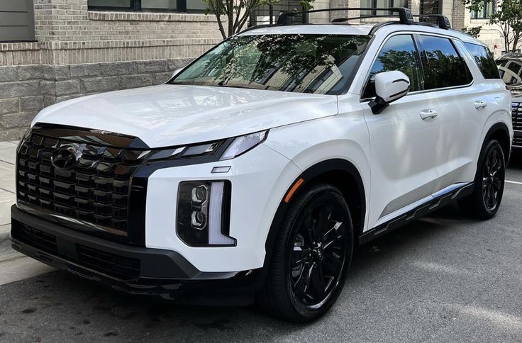 a white suv is parked on the side of the road in front of a building