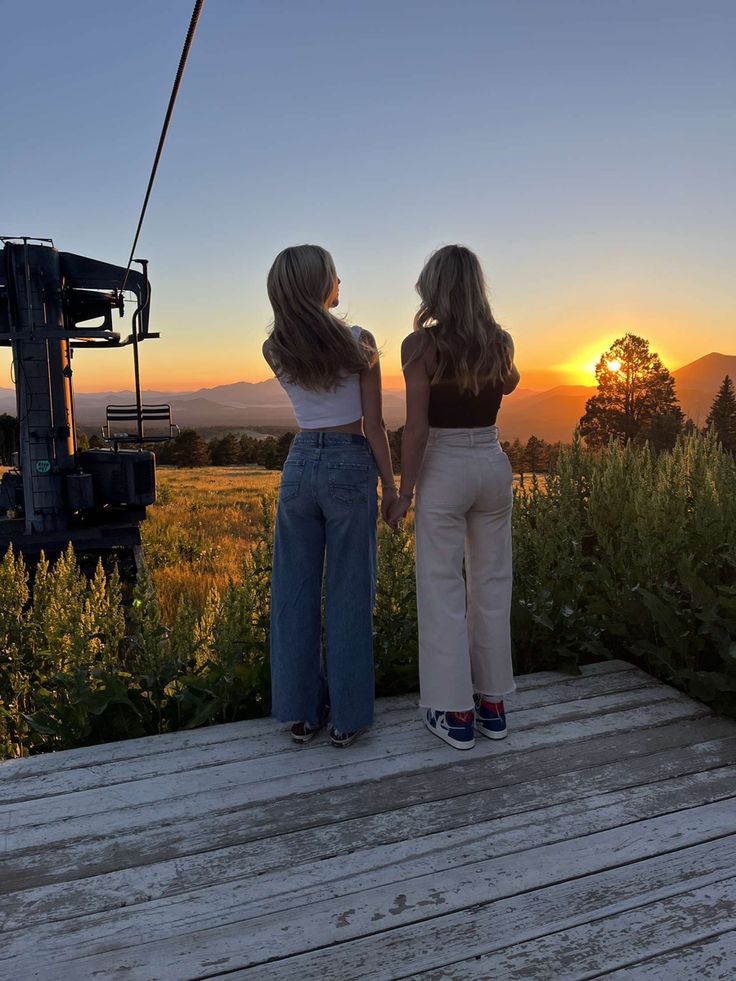 two women standing on a deck looking at the sunset