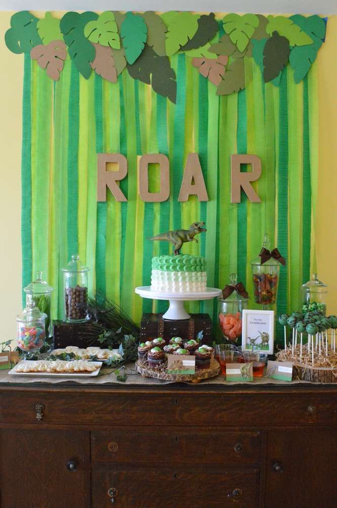 a table topped with lots of desserts next to a green wall covered in paper