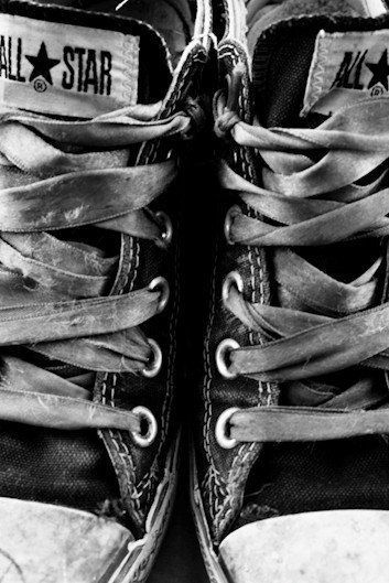 black and white photograph of an old pair of sneakers with laces on the bottom