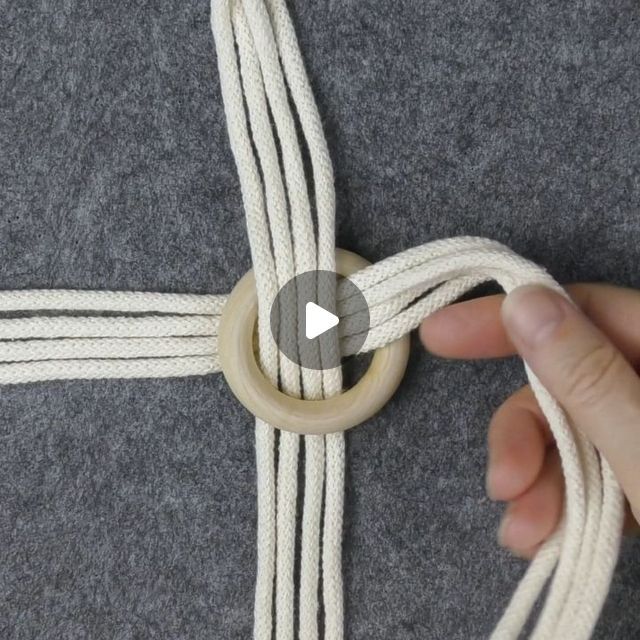 someone is tying a rope around a piece of fabric with a wooden ring on it