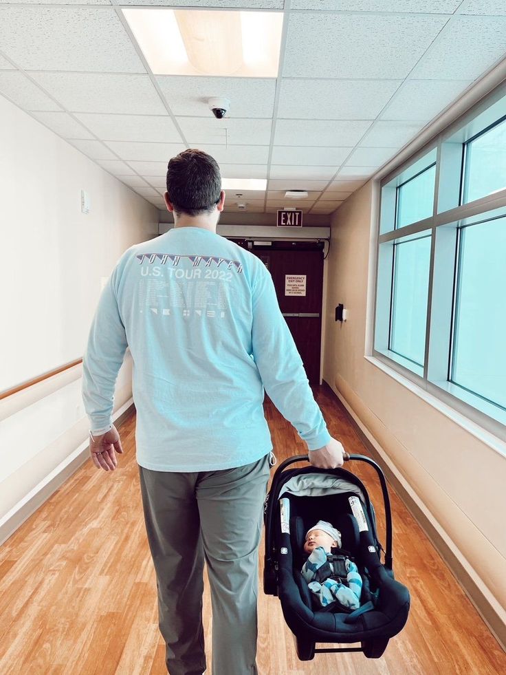 a man walking down a hallway with a baby in a stroller