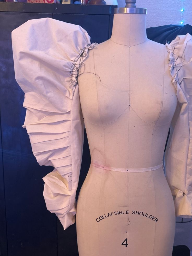 a mannequin with ruffled sleeves and collars on display in a shop
