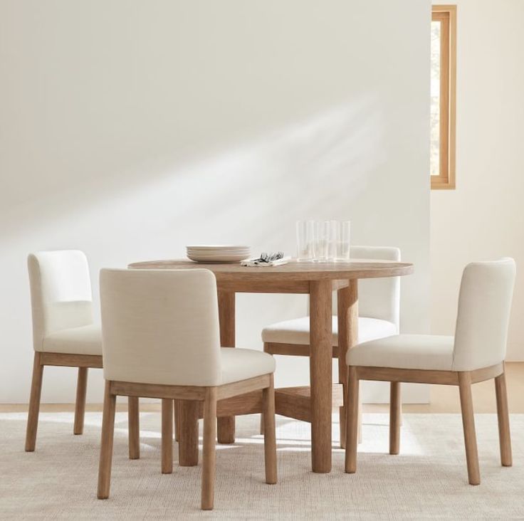 a dining table with four chairs and a bowl on top of it in front of a white wall