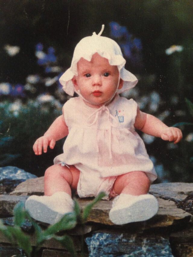 an old photo of a baby sitting on a rock