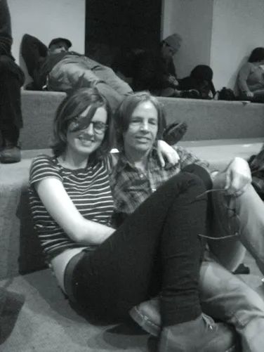 two people are sitting on the floor with their legs crossed and looking at the camera