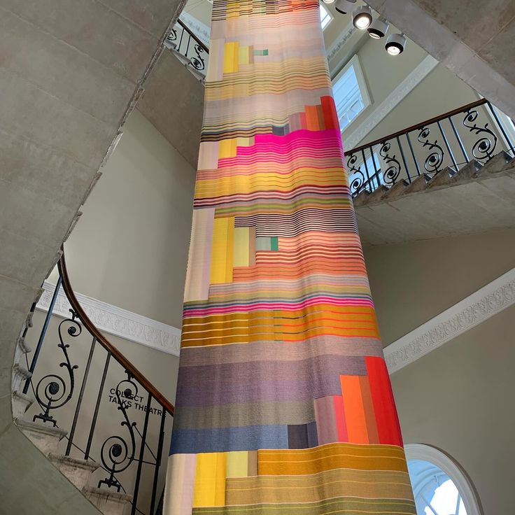 a multicolored curtain hanging from the ceiling in a room next to a spiral staircase