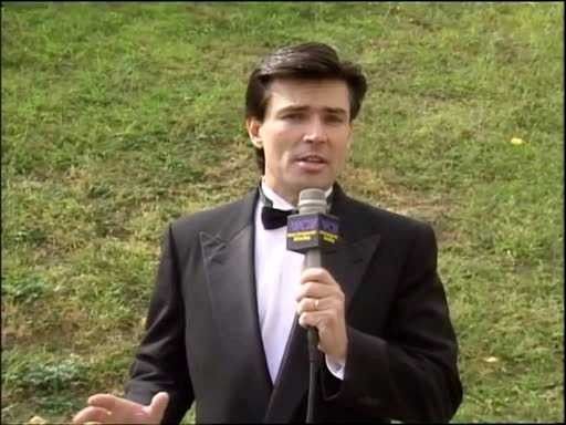 a man in a tuxedo holding a microphone