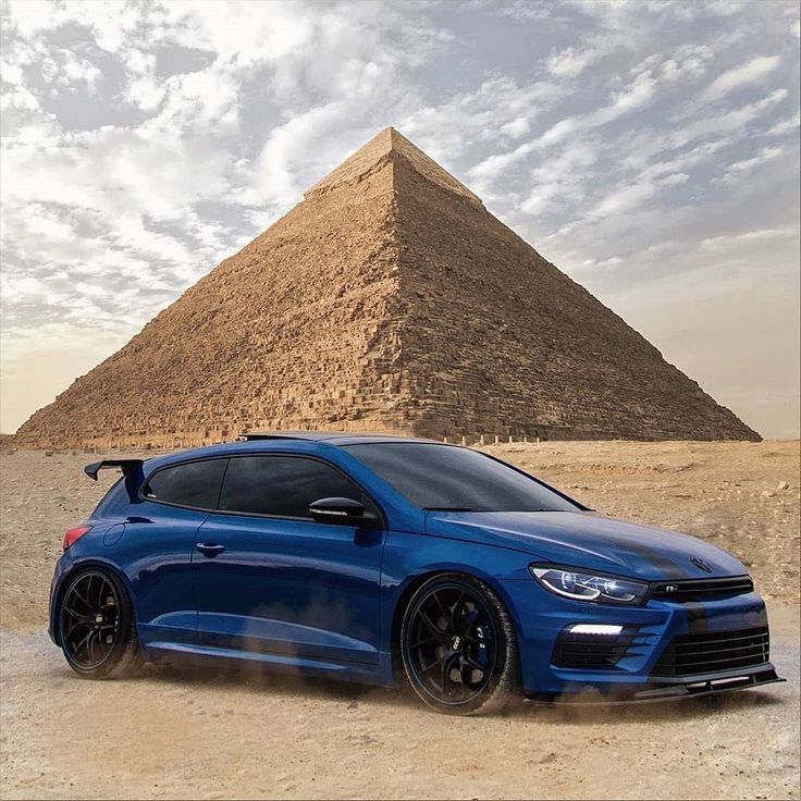 a blue car parked in front of a pyramid