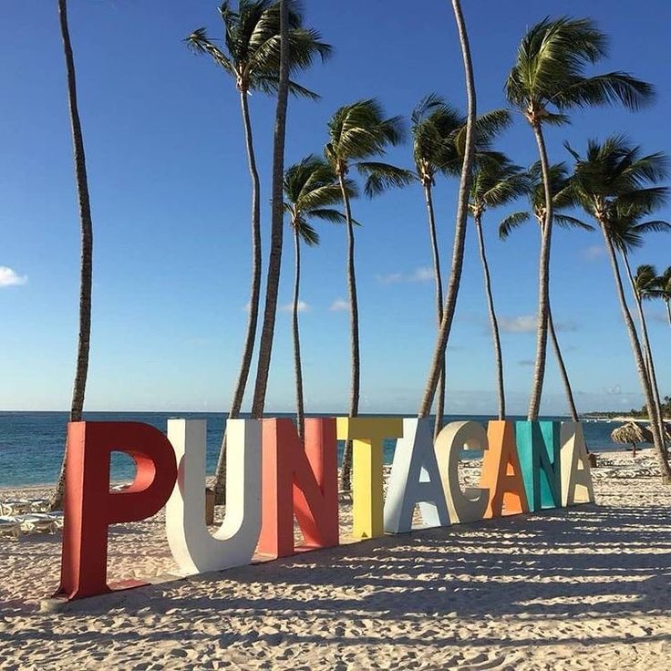 a sign that says punta on the beach next to palm trees