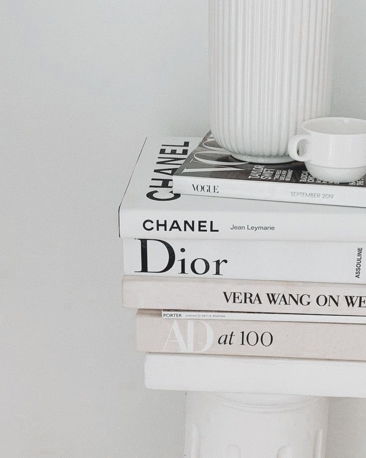 three books stacked on top of each other next to a white cup and saucer