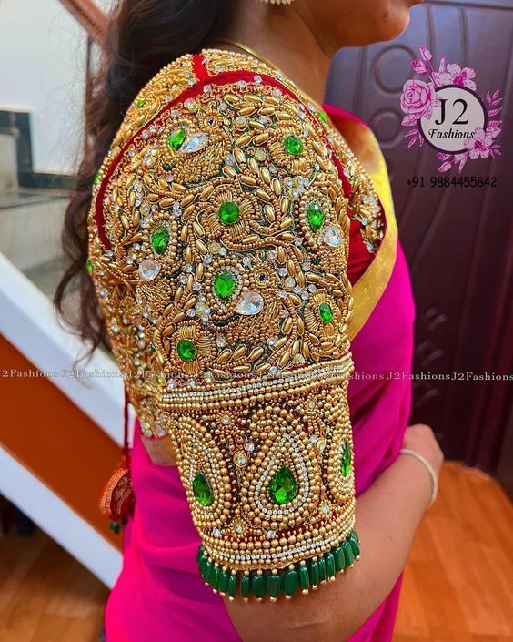 a woman wearing a pink sari with green and gold jewelry on her arm,