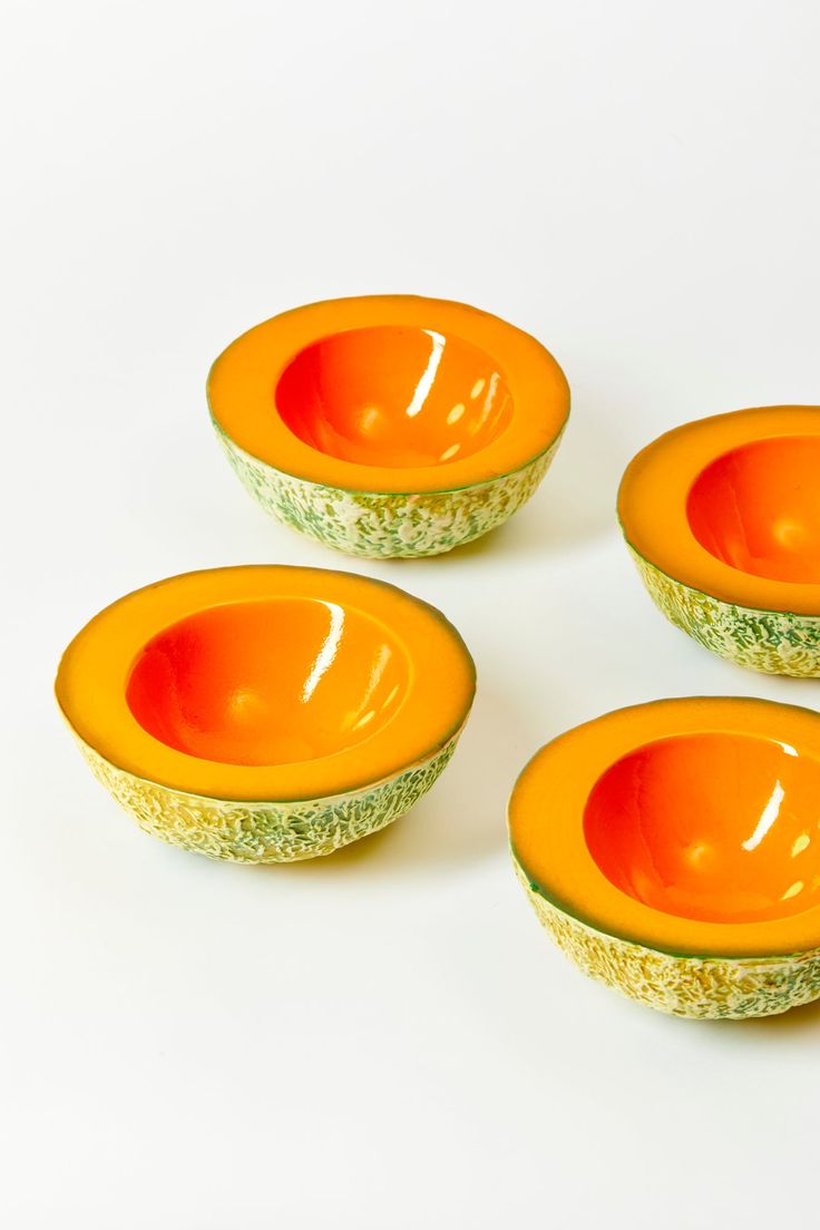 four orange and green bowls sitting on top of each other in front of a white background