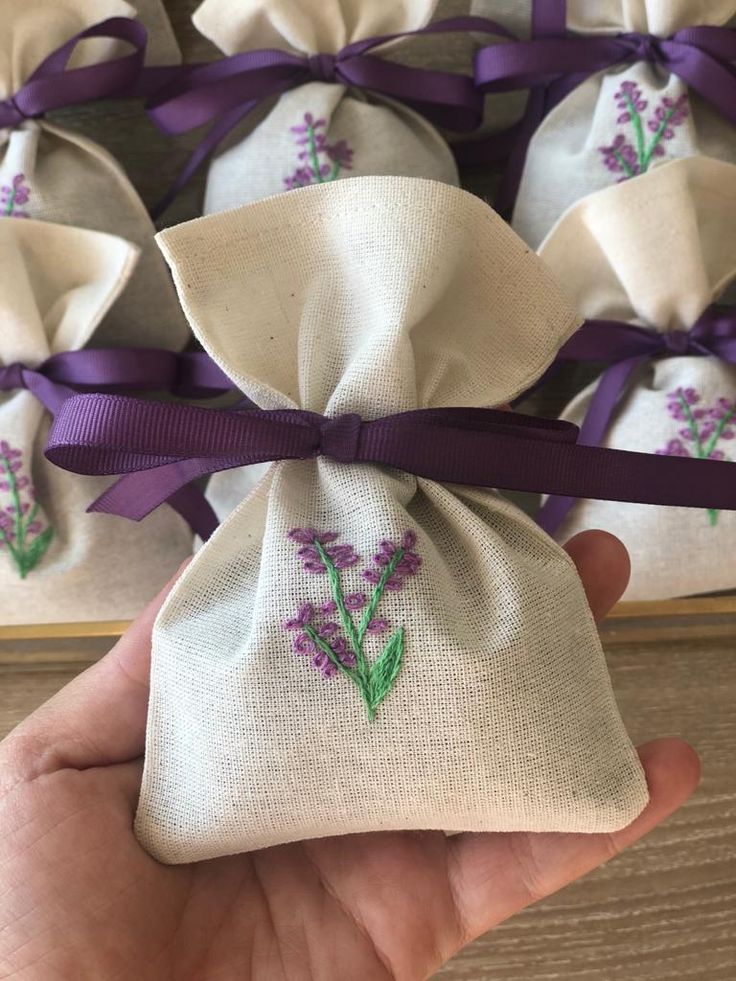 a hand holding a small bag with purple flowers on it