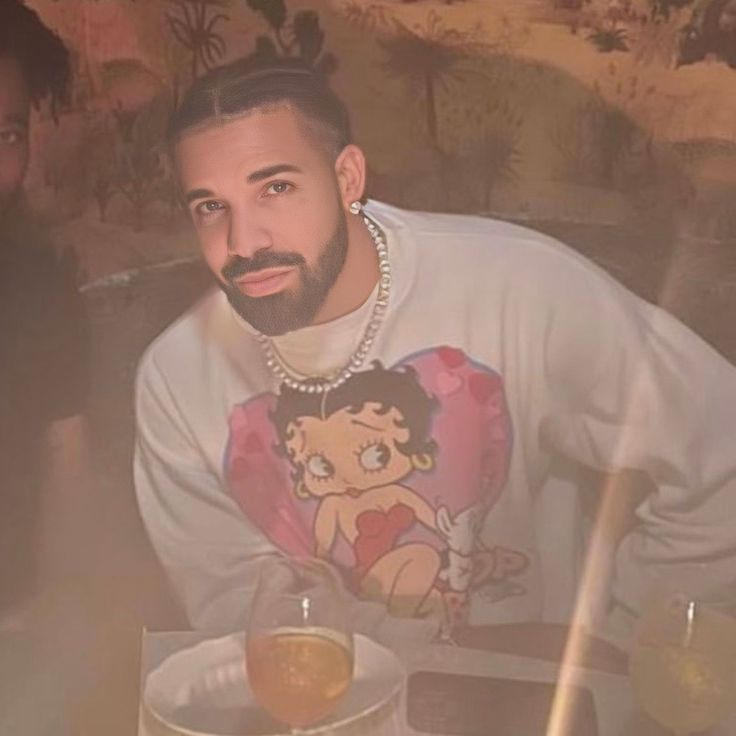 a man sitting at a table with a drink in front of him and another person behind him