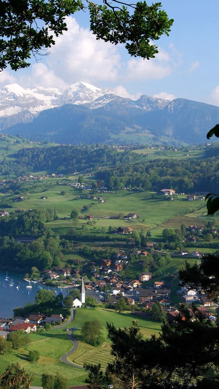 a scenic view of a small town with mountains in the back ground and water below