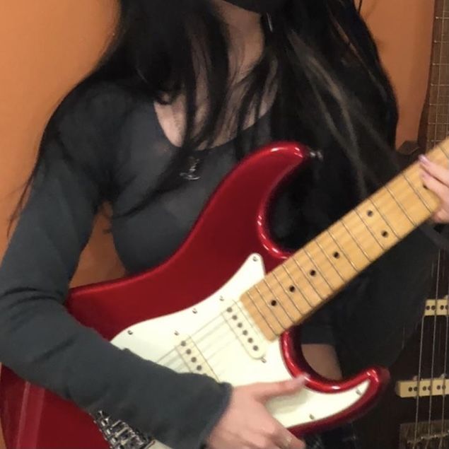 a woman with long black hair is holding a red and white guitar in her hands
