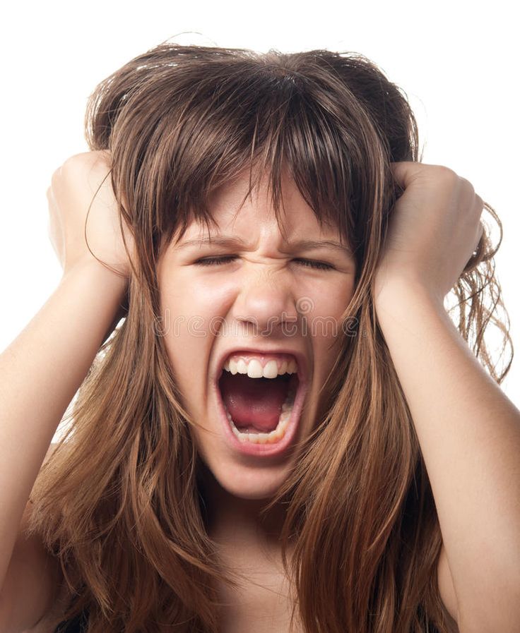 a young woman with her hands on her head screaming and holding her hair in front of her face
