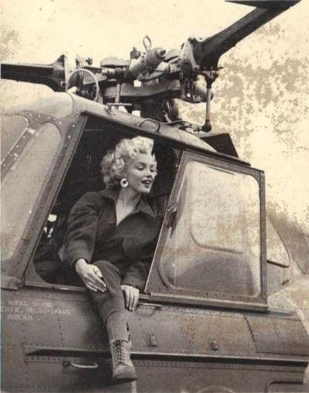 an old black and white photo of a woman sitting in the cockpit of a helicopter