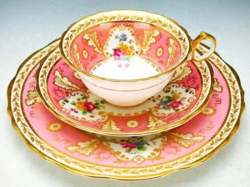 a pink and gold tea set with matching saucers