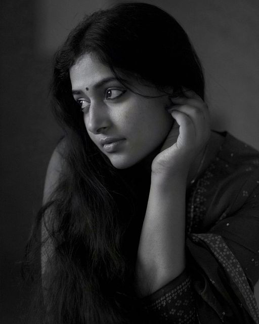 a black and white photo of a woman with her hand on her chin looking at the camera