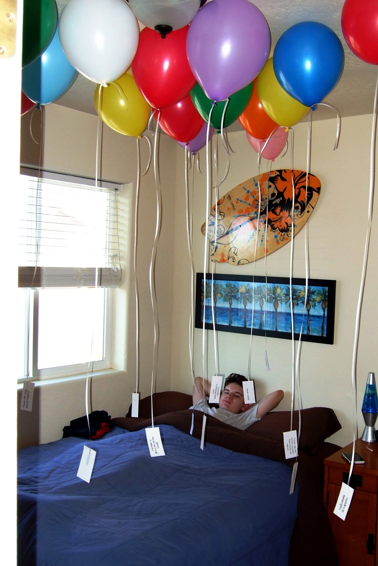 a man laying in bed with lots of balloons attached to the ceiling above his head