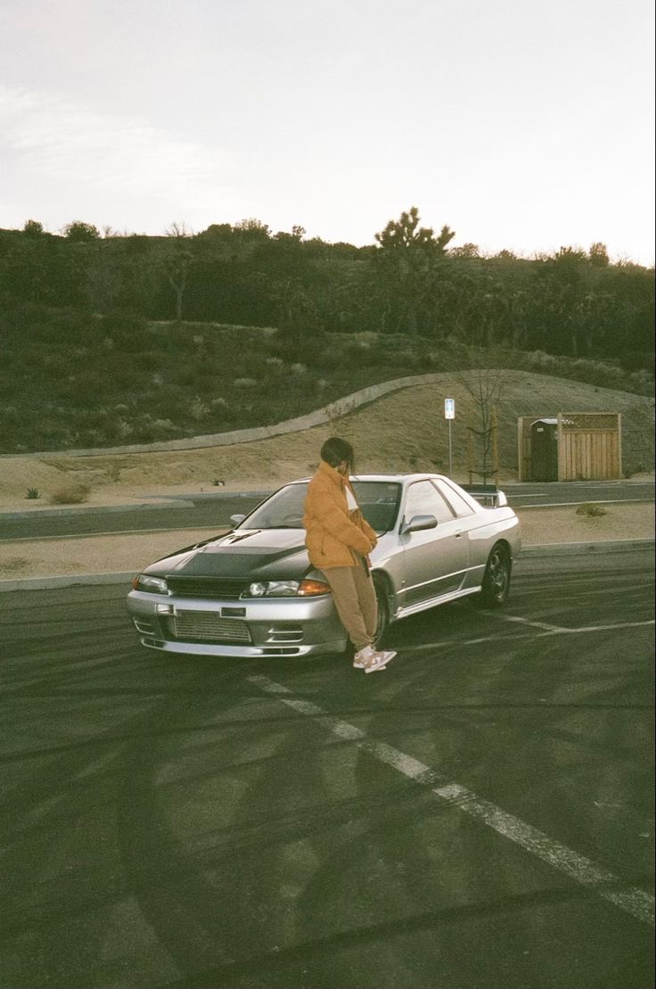 a man standing next to a car in a parking lot