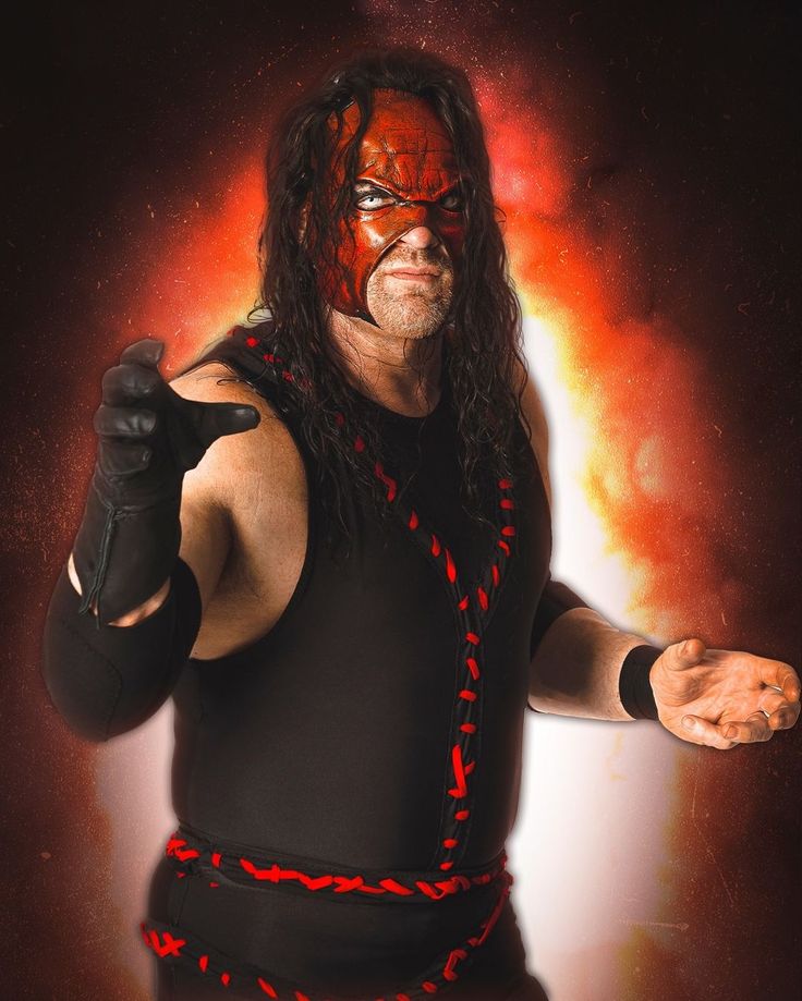 a man with long hair wearing a red and black wrestling ring on his chest, holding two hands out in front of him