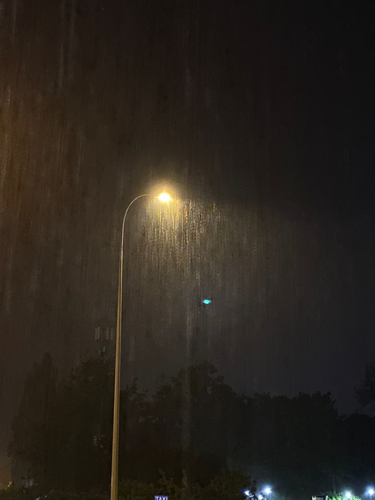 the street light is lit up on a rainy night with no one in it yet