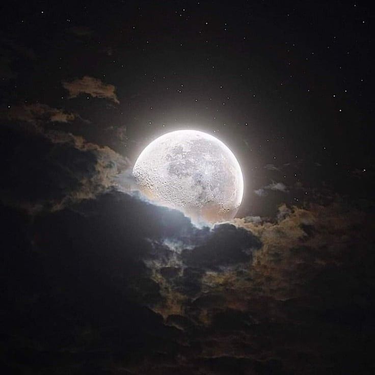 the full moon is shining brightly in the night sky with clouds and stars around it