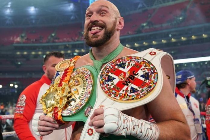 a man holding two boxing belts in his hands