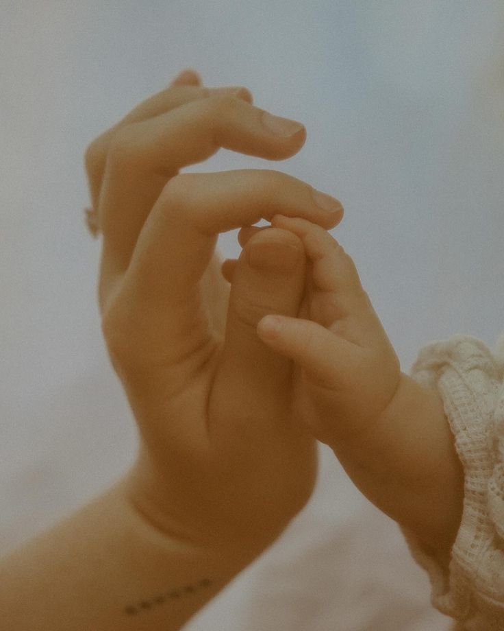 a baby holding the hand of an adult