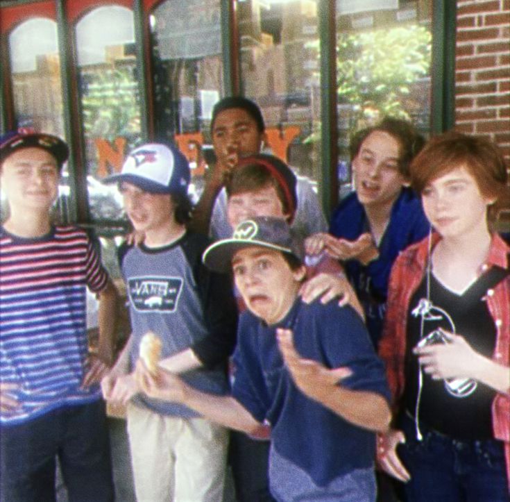 a group of young people standing next to each other in front of a store window