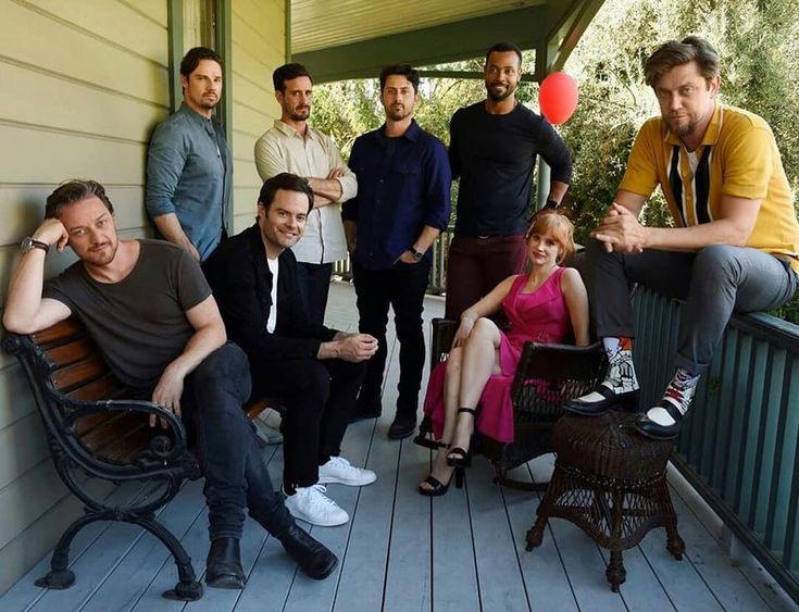 a group of men and women sitting on top of a porch next to each other