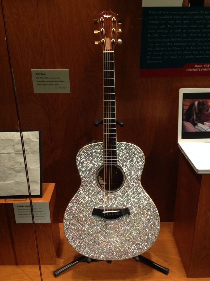 an acoustic guitar is on display in a glass case with wood paneling behind it