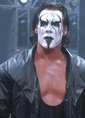 a man with white face paint on his face standing in front of a stage wearing a black leather jacket