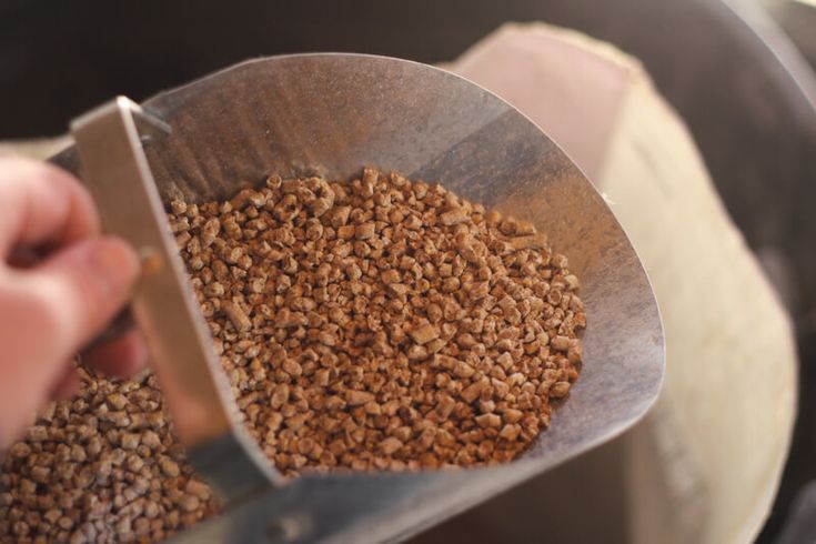 a person holding a large metal scoop full of brown grains with a knife in it