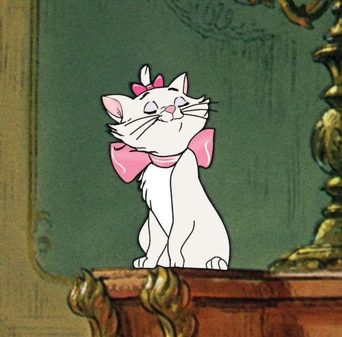 a cartoon cat with a pink bow sitting on top of a wooden table next to a lamp