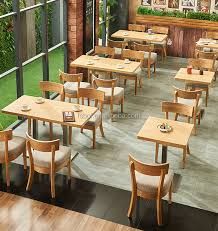 an empty restaurant with wooden tables and white chairs, green plants on the windowsill